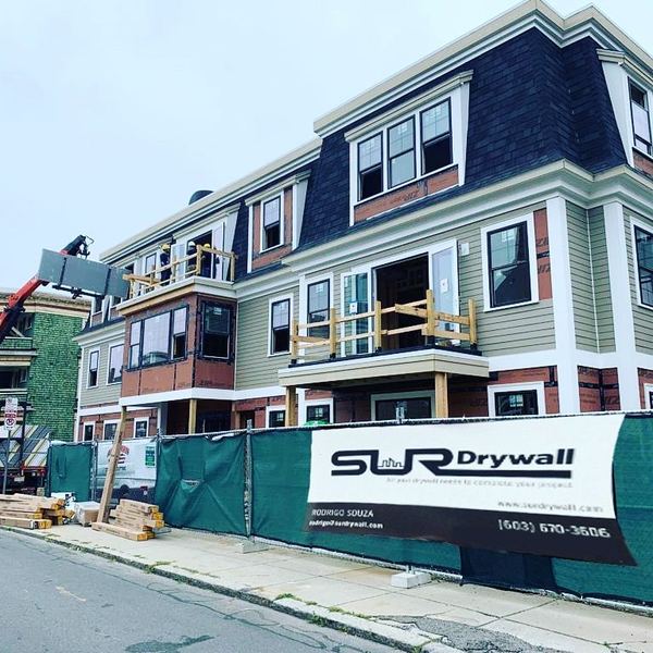 Multifamily building with a SUR Drywall banner on the fence